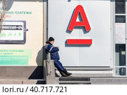 An elderly man stands between the branches of Sberbank and AlfaBank and chooses a Bank for himself (2019 год). Редакционное фото, фотограф Сергей Сергеев / Фотобанк Лори