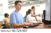 Clever focused male teenager solving tasks of computer science in the auditory. Стоковое видео, видеограф Яков Филимонов / Фотобанк Лори