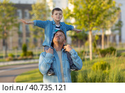 child sits on his father's shoulders while walking through the streets of the city. Стоковое фото, фотограф Ирина Михайличенко / Фотобанк Лори
