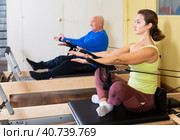 Woman pulling stretch band sitting on pilates training machin. Стоковое фото, фотограф Яков Филимонов / Фотобанк Лори