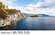The rocky shore of Lake Baikal in autumn. Flying over the water to the Shaman Cape. Clear water, trees with bright yellow leaves. Скалистый берег озера Байкал осенью. Полет над водой к Шаманскому мысу. Прозрачная вода, деревья с ярко-желтыми листьями. Стоковое видео, видеограф Виктория Тельминова / Фотобанк Лори