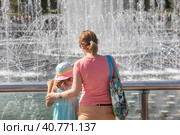 Мама с дочкой смотрят на фонтан в парке Царицыно в жаркий летний день в городе Москве, Россия (2023 год). Редакционное фото, фотограф Николай Винокуров / Фотобанк Лори