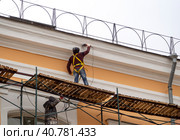 Building facade renovation. The worker stands on the scaffolding and works the surface with a power tool. Стоковое фото, фотограф Бузмакова Светлана / Фотобанк Лори