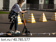 Девушка  учится ездить на самокате на площадка обучения вождению электросамокатов сервиса аренды самокатов компании Whoosh на территории спортивного комплекса Лужники в городе Москве, Россия (2023 год). Редакционное фото, фотограф Николай Винокуров / Фотобанк Лори