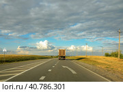 Грузовик, уезжающий вдаль по пустой асфальтированной дороге. Lone truck van receding along the asphalt road out of town toward the horizon. Beautiful blue sky with lots of clouds. Стоковое фото, фотограф Валерий Елистратов / Фотобанк Лори