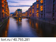 Hamburg city old port during blue hour, Germany, Europe. Historical famous warehouse district artificial illuminated. Water castle palace mirrored on river surface (2018 год). Стоковое фото, фотограф Igor Tichonow / Фотобанк Лори