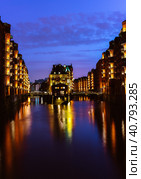 The Warehouse District - Speicherstadt in twilight. Tourism landmark of Hamburg. View of Wandrahmsfleet in light of lantern lamp. Port of Hamburg within the HafenCity quarter (2018 год). Стоковое фото, фотограф Igor Tichonow / Фотобанк Лори