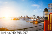 Panorama of hafencity - Red light lantern in front. Blue sky bright sky with evening sun light. Port piers with ships and yacht at anchor. Hamburg, Germany (2018 год). Стоковое фото, фотограф Igor Tichonow / Фотобанк Лори
