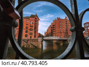 Speicherstadt warehouse district in Hamburg, Germany, Europe. Old brick buildings and channel of Hafencity quarter. UNESCO heritage. Shoot thought cast-iron creative concept (2019 год). Стоковое фото, фотограф Igor Tichonow / Фотобанк Лори