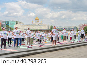 Московские пенсионеры в фирменных московских футболках и шапочках, участники программы «Московское долголетие, делают гимнастику в парке Музеон на фоне храма Христа Спасителя, голубого неба и красивых кучевых облаков (2023 год). Редакционное фото, фотограф Сергей Никифоров-Гордеев / Фотобанк Лори
