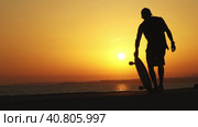 Silhouette of a man near the ocean with a longboard at bright orange sunset. Стоковое видео, видеограф Константин Шишкин / Фотобанк Лори