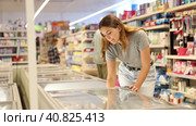 Woman buyer carefully chooses frozen food in grocery store freezer. Стоковое видео, видеограф Яков Филимонов / Фотобанк Лори