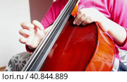 Picicato on the cello. A child girl in a pink jacket plays pizzicato with her fingers the cello without a bow. An entry-level violoncello study at a music school. Стоковое видео, видеограф Юлия Петровская / Фотобанк Лори