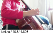 Picicato on the cello. A child girl in a pink jacket plays pizzicato with her fingers the cello without a bow. An entry-level violoncello study at a music school. Стоковое видео, видеограф Юлия Петровская / Фотобанк Лори