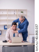 Old male boss and young male employee in bullying concept. Стоковое фото, фотограф Elnur / Фотобанк Лори