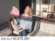 Exhausted middle aged woman using paper waver, suffering from hot summer. Стоковое фото, фотограф Гладских Татьяна / Фотобанк Лори