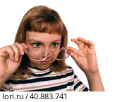 Cute 7 year old Caucasian girl looks into glasses. Eyes in a bunch. Ophthalmic problems in children. Myopia, exophoria and astigmatism. Selection of glasses. Isolate white background. Back to school. Стоковое фото, фотограф Юлия Петровская / Фотобанк Лори