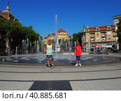 Subotica, Serbia, September 12, 2021. Fountain on the square of Subotica near the City Hall. Schoolchildren, boy and girl, brother and sister are standing and smiling. Стоковое фото, фотограф Юлия Петровская / Фотобанк Лори