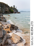 Baikal Lake in summer. Due to the earthquake, screes of coastal rocks arise. Sandy beach of Olkhon Islands with waves crashing against the rocks. Scenic seaside landscape. Natural background. Стоковое фото, фотограф Виктория Катьянова / Фотобанк Лори
