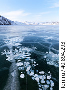 Beautiful winter landscape of frozen Baikal Lake in cold winter day. Blue ice fields with white bubbles and cracks in iced Anga bay. Natural seasonal background. Winter ice travel and active outdoors. Стоковое фото, фотограф Виктория Катьянова / Фотобанк Лори