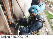 Two industrial mountaineering laborers in uniform and helmets hanging over residential building facade. Workers working on wall, access high rise work. Industry urban work concept. Copy ad text space. Стоковое фото, фотограф Aleksandr Golubev / Фотобанк Лори