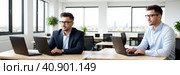 Concentrated two businessmen at table, involved in serious negotiations or contract discussion in office. Focused male ceo executive manager communicating with partner or client, banner. Generative AI. Стоковое AI-изображение, AI-художник Sergey Grishin / Фотобанк Лори