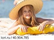 Happy cute smiling little girl in straw hat lying on the sand on a beach in a swimsuit. Summer concept. Стоковое фото, фотограф Ирина Михайличенко / Фотобанк Лори