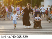 Moscow, Russia - July 23 2022: People on the Moscow city street in hot summer day. Modern young beautiful mother walking with two babies and grandmother, Lifestyle concept. Редакционное фото, фотограф YuryKara / Фотобанк Лори