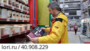 Buyer selects paint and plaster in the store (2018 год). Редакционное фото, фотограф Анна Кривицкая / Фотобанк Лори