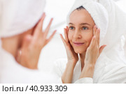 portrait of gorgeous happy middle age woman looking at mirror touching her skin. Стоковое фото, фотограф Гладских Татьяна / Фотобанк Лори
