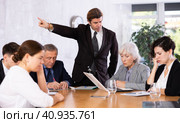 Furious male boss yelling at office colleagues of different ages taking notes at table with laptops. Стоковое фото, фотограф Яков Филимонов / Фотобанк Лори
