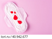 Женская гигиеническая прокладка с красными сердечками на розовом фоне. Концепция менструаций, гигиены. Место для текста. Стоковое фото, фотограф Айгуль Миннибаева / Фотобанк Лори