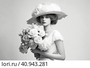 Light monochrome modern beautiful woman in 1910s fashion style with hourglass waist, voluminous skirt and wide hat decorated with flowers and veil.  Generative AI. Стоковое AI-изображение, AI-художник Анна Кривицкая / Фотобанк Лори