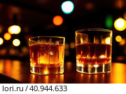 Two orange campari cocktails (Old-Fashioned Negroni Aperol Spritz) with ice on a contrast turquoise background, vertical. Light through the liquid. Top down view. Generative AI. Стоковое AI-изображение, AI-художник Sergey Grishin / Фотобанк Лори