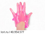 Hand Playing with textured slime with bubbles, stretching the gooey substance. Female teen hand holding pink shining slime, squeezing it. Adorable Girl stretching slime toy to the sides. Liquid toy. Стоковое фото, фотограф Марина Демидюк / Фотобанк Лори