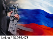 Russian assault rifle in the hands of a Russian soldier against the background of the flag of the Russian Federation. The concept of mobilization and defense of the motherland. Selective focus. Стоковое фото, фотограф Алексей Игнатов / Фотобанк Лори