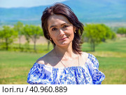 Slender 45 year old Russian smiling brunette woman in blue dress in russian slavic style on a green field. Copy space. Стоковое фото, фотограф Татьяна Терехина / Фотобанк Лори