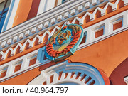 Coat of arms of the USSR on the facade of an old building in red and white. The inscriptions on the ribbon in different languages of the world: Proletarians of all countries, unite. Стоковое фото, фотограф Алексей Игнатов / Фотобанк Лори