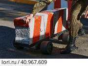 Road checkpoint. The soldier moves the barrier. Control of the movement of vehicles during a special operation. Special device on the road. The mobile block on wheels for the pass of cars. Стоковое фото, фотограф Алексей Игнатов / Фотобанк Лори