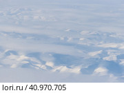 Вид с воздуха на заснеженные горы и облака. Зимний горный пейзаж. Ичигемский хребет, Колымское нагорье. Корякский округ (Корякия), Камчатский край, Сибирь, Дальний Восток России. Отличный фон. Стоковое фото, фотограф Андрей Степанов / Фотобанк Лори