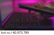 Use of mobile phone in trendy neon lights with laptop. Creative vivid color of ultraviolet red and blue. Hands of Girl scrolling up photos Close-up at dark room. App for sale in shop, Social media. Стоковое видео, видеограф Марина Демидюк / Фотобанк Лори