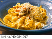 Pasta, bavette with nuts, garlic, olive oil. Side view, close-up. Pasta with parmesan cheese. Delicious spaghetti served on a blue ceramic plate. Alfredo pasta dinner, creamy white sauce. Tagliatelle. Стоковое фото, фотограф Марина Демидюк / Фотобанк Лори