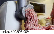 A meat grinder for chopping fresh raw meat works against the background of the kitchen.  Focus on a working meat grinder. Стоковое видео, видеограф Ярославский Максим / Фотобанк Лори