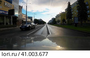 Ранним солнечным утром после дождя машина движется по пустынному проспекту Ленина у ТЦ Макси в сторону Онежского озера в городе Петрозаводске. Вид с машины в движении (2023 год). Редакционное видео, видеограф Sergei Gorin / Фотобанк Лори