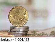 Деньги. Монета номиналом в 10 рублей на стопке монет в 1 рубль на фоне купюр. Стоковое фото, фотограф E. O. / Фотобанк Лори