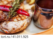 Grilled chicken, baked with potatoes and chili pepper. Food is served on a platter with tomato sauce and decorated with rosemary branch. Курица-гриль, запеченная с картофелем и перцем чили. Блюдо подается на блюде с томатным соусом и украшается веточкой розмарина. Стоковое фото, фотограф Дмитрий Березнев / Фотобанк Лори