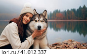 Young girl with her Siberian Husky dog sits hugging on the shore of a mountain lake on an autumn evening. Стоковое AI-изображение, AI-художник Мария Мороз / Фотобанк Лори