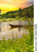 Wooden boat in on the lake among yellow flowers in Vietnam under sunset. Стоковое фото, фотограф Татьяна Терехина / Фотобанк Лори