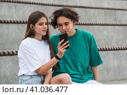 Young couple together listening to the same music through headphones, sitting in empty stands. Стоковое фото, фотограф Евгений Харитонов / Фотобанк Лори