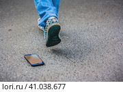 Потерянный телефон на асфальте и ноги уходящего человека. Смартфон выпал на дорогу. Утеря мобильного телефона. Стоковое фото, фотограф Константин Григорьев / Фотобанк Лори